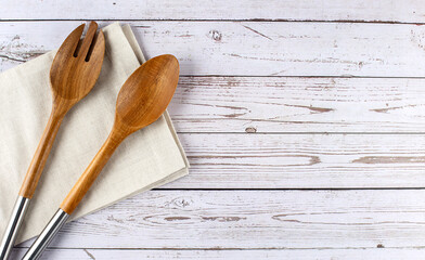 Two wooden salad spoons on napkin on a wooden background, flat lay, copy space