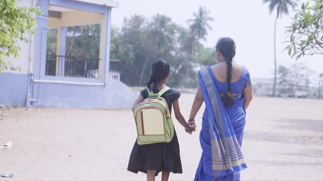 Back view shot of mother leaving daguther to school by holding hand - concept of motherhood, education and parental caring.