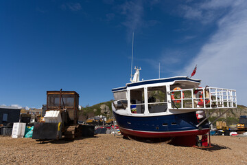 A small fishing boat on the beach at Hasting in East Sussex with fishing equipment in view on the...