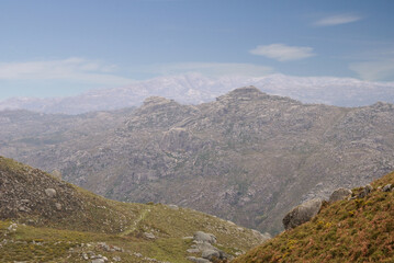 Fototapeta premium Paisagem de montanha, colinas com vegetação verde flores amarela e pedras nas colinas, alturas céu azul com nuvens