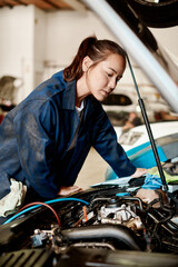Its my job to solve challenging problems. Shot of a female mechanic working on a car in an auto...