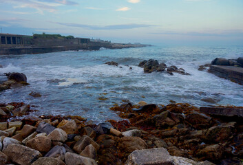 Sea foam on the waves along a rocky coastline in Ireland at dusk.