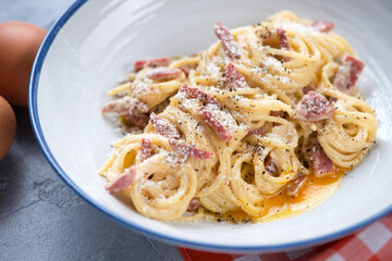 Close-up of spaghetti alla carbonara served in a white plate, selective focus, studio shot