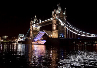 Night scene of Tower Bridge opening to admit a boat.