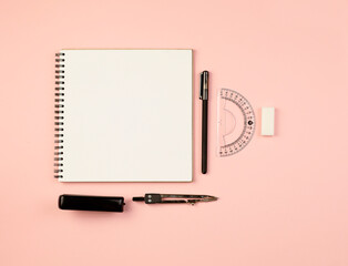 Flat layout. Spring notepad, pen, eraser, ruler, stapler, compasses on a pink background on a pink...