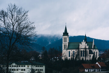 church in the Polish city of Mszana Dolna against the mountains and clouds - obrazy, fototapety, plakaty