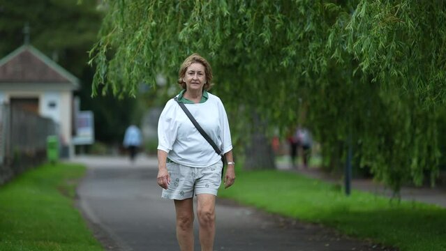One older woman walking outside in park senior person walks outdoors in nature