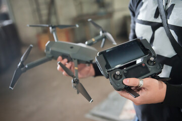 Man holding transmitter with attached mobile device and drone - Powered by Adobe
