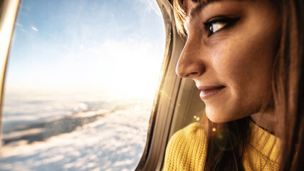 Young woman airplane passenger looking the sky from cabin window - Female tourist enjoying flight...