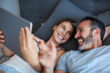 Our kids will be cute just like these. High angle shot of an affectionate couple using a digital tablet while lying in bed together in the morning.