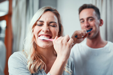 Gotta keep them whites extra bright. Portrait of a young couple brushing their teeth together in...