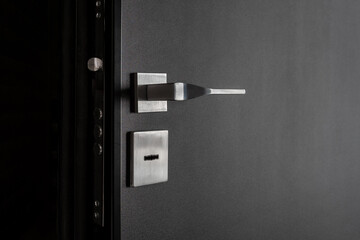 Light metal handles and door lock on a black metal door