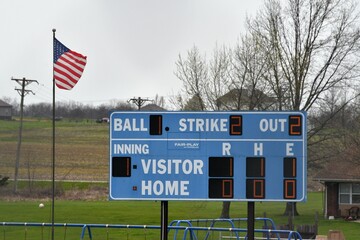 American Flag by a Blue Baseball Scoreboard