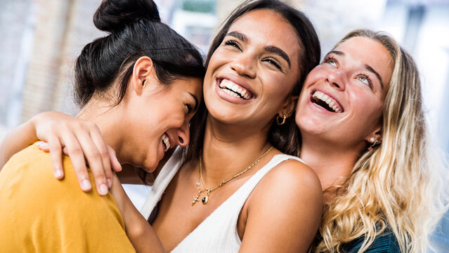 Three happy women smiling together outdoors - Multicultural girls having fun on city street - Happy friendship concept with females enjoying day out
