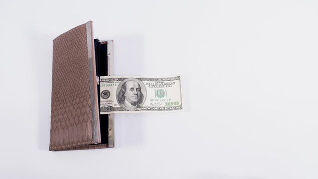 A brown leather wallet catches up and swallows a hundred dollar bill. The concept of business, earning, attracting money, increasing wealth. Stop motion animation.