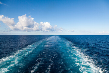 The trail from the movement of the ship in the sea stretching into the horizon with a clear sky...