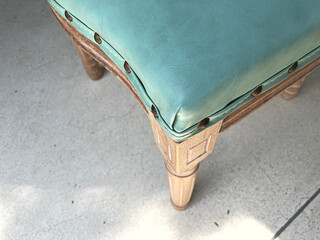 Close up detail of blue leather, wooden chair on concrete floor.