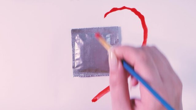 Drawing a heart around a condom in a silver package on a white background. The concept of safe sex, birth control, prevention of AIDS and STDs.
