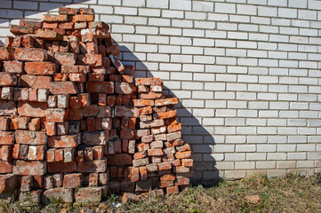 Dismantled wall of a building made of old sand-lime brick against the background of a new wall