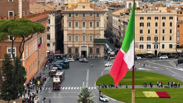 Aerial shot of traffic on roundabout in old town of Rome - In foreground italian flag - View from Altar of Fatherland