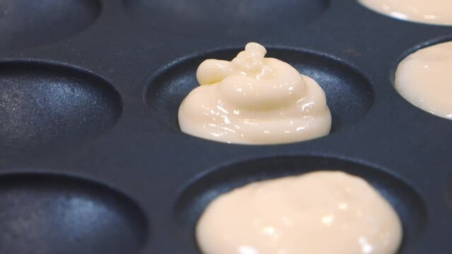 Mini pancake toaster. Process for making a mini pancakes. Hand of a girl pouring a mixture for mini pancakes.