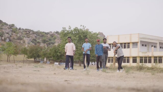 establishing shot, group of college students with bat and ball coming to play cricket - conept of refreshment, physical activity and relaxation or weekend activities