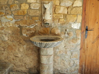 fuente con pie cilíndrico y pica circular, con un caño saliendo de la boca de un pez, tarrés,...