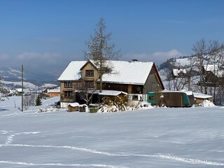 Traditional Swiss architecture and wooden alpine houses in the winter ambience of fresh white snow cover, Nesslau - Obertoggenburg, Switzerland (Schweiz)