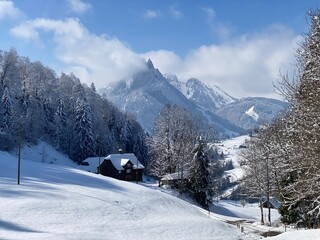 Fototapeta premium Traditional Swiss architecture and wooden alpine houses in the winter ambience of fresh white snow cover, Nesslau - Obertoggenburg, Switzerland (Schweiz)