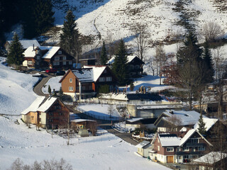 Traditional Swiss architecture and wooden alpine houses in the winter ambience of fresh white snow cover, Nesslau - Obertoggenburg, Switzerland (Schweiz)