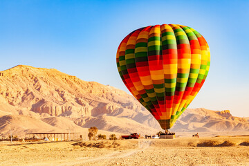 Fototapeta na wymiar View of colorful hot air balloons with passengers landing on the plane at Valley of The Kings in the morning, Luxor, Upper Egypt.