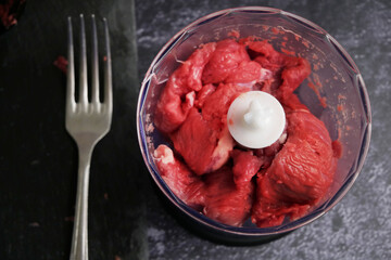 fresh raw ground beef meat heap and meat grinder on black background. Top view