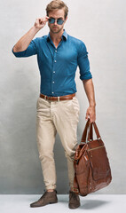 On his way in style. Full length portrait of a handsome young man posing with a bag in the studio.