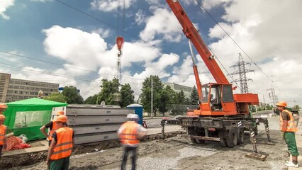 Unloading concrete plates from truck by crane at road construction site timelapse.