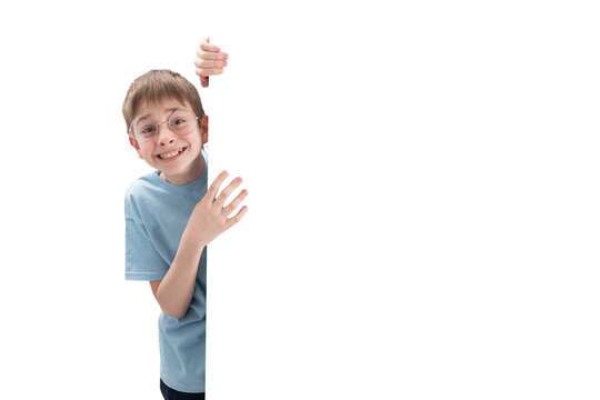 Happy smiling preteen boy peeks out from behind whiteboard with an empty white space for your text or announcement. Copy space. Isolate