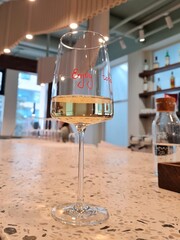White wine of golden color in a wine glass on the bar counter of a restaurant