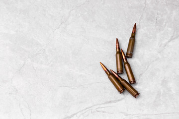 Fototapeta na wymiar Bullets on a gray background. Cartridges of caliber 7.62 for the Kalashnikov assault rifle. View from above. Close-up. Space for copy. Flat composition. Military concept.