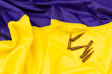 Bullets on the background of the Ukrainian flag. Composition with cartridges and a magazine for a...