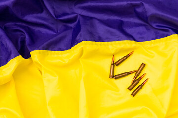 Bullets on the background of the Ukrainian flag. Composition with cartridges and a magazine for a machine gun. Cartridges of caliber 7.62 for a Kalashnikov assault rifle. Top view. Close-up. 