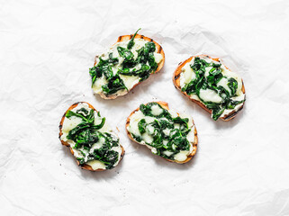 Hot sandwiches with spinach and mozzarella on a light background, top view