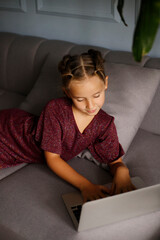 Pretty teenager girl lying on sofa in front of a laptop with. Online education distance concept