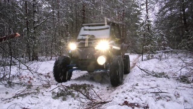 Two utv sxs off-road vehicles with the headlights on in the evening snow forest