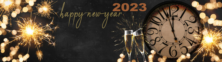 HAPPY NEW YEAR 2023 - Festive silvester New Year's Eve Party celebration background panorama banner long - Golden yellow fireworks, sparklers, clock and champagne classes toasting in dark black night