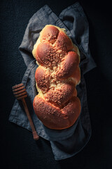 Homemade and sweet golden challah on dark table for breakfast.