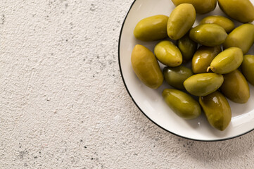 Green pickled olives on a light background, space for text, close-up