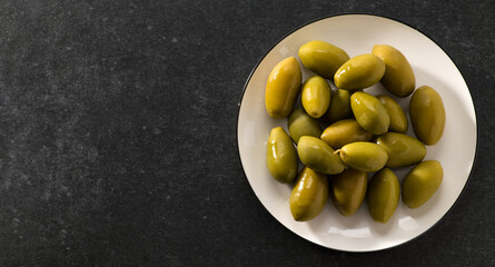 Green pickled olives on a dark gray background, banner, space for text, top view