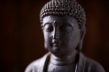 Meditating Buddha Statue on dark wooden background. Close up. Copy space.	