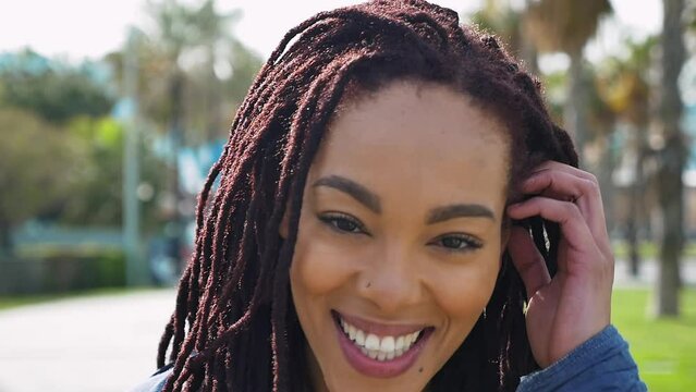 Young beautiful woman with dreadlocks hairstyle smiling at camera.