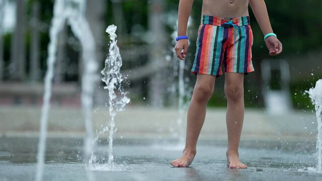 Child at public water fountain during summer day