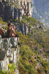 Problems seem a lot smaller when youre out in the mountains. Shot of a woman using binoculars while...